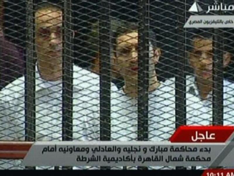 Alaa (C) and Gamal (L) Mubarak are seen in their 'family cage'. Bystanders observed Alaa to be clutching on to a Koran for much of the proceedings.