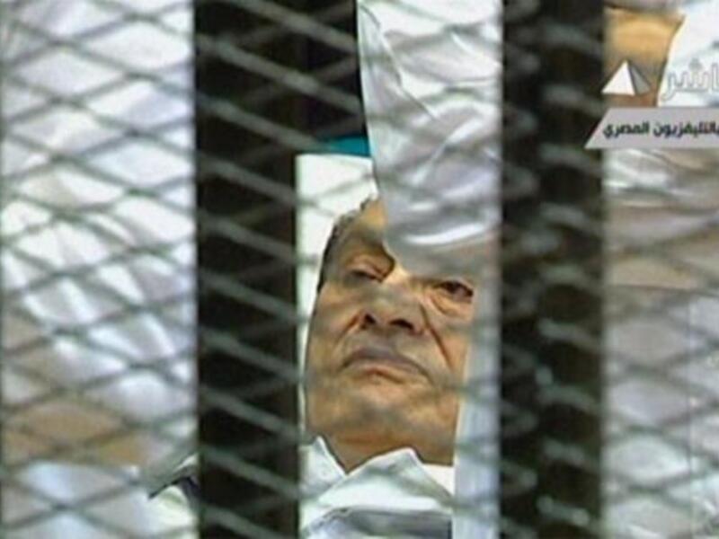 Egyptian former president Hosni Mubarak lies on a stretcher as he listens to the opening proceedings in a holding cell in the court room in the police academy. Comments emerging by the news-hungry public and media highlighted his dyed black hair- in spite of his invalid and ailing condition.