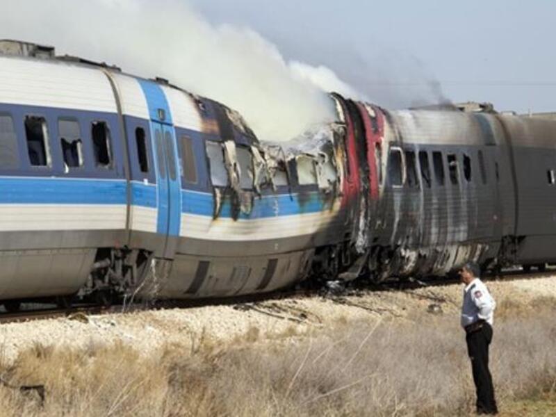 An Israeli policeman stands next to a burning train coach near Kibbutz Shfaim.