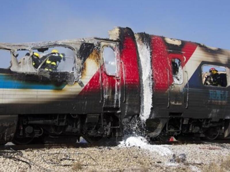 Israeli fire fighters spray water to extinguish the flames of a burning train coach near Kibbutz Shfaim, close to the Israeli city of Netanya.