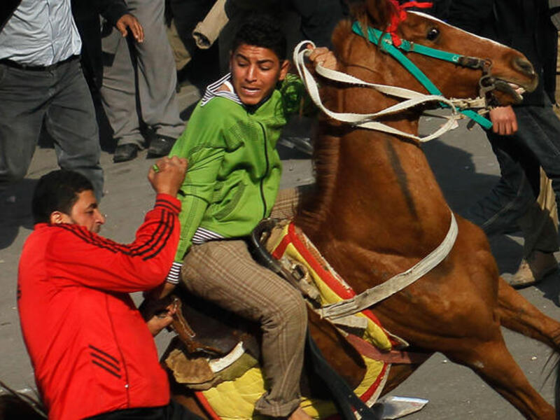 An opponent of embattled Egyptian president Hosni Mubarak (L) attacks a horse-riding pro-Mubarak supporter, pulling him off his horse during a clash between pro- and anti-Mubarak protesters.
