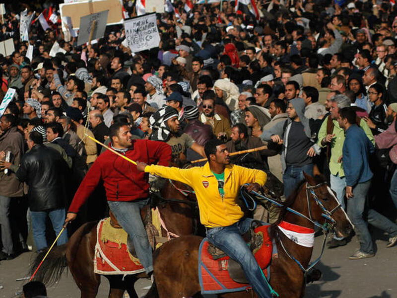 Supporters of embattled Egyptian president Hosni Mubarak ride horses through the melee during a clash between pro- and anti-Mubarak protesters.
