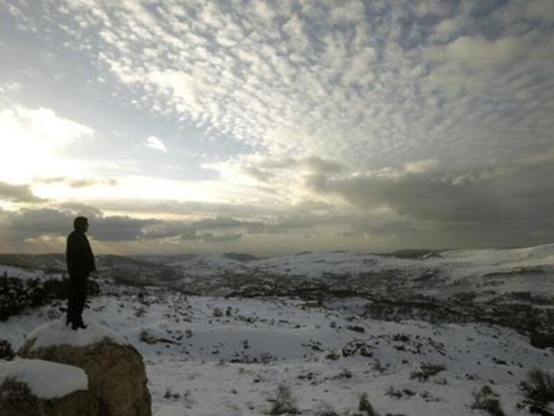 A Lebanese forest ranger observes the sunset from the cedar trees reserve of Baruk in the Shouf mountains, southeast of Beirut, following a snow storm and cold wave which hit the east Mediterranean country after several months of drought.