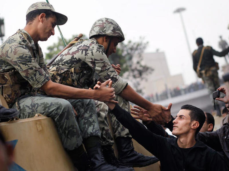 Marchers shake hands with Egyptian Army soldiers on tanks during a demonstration.