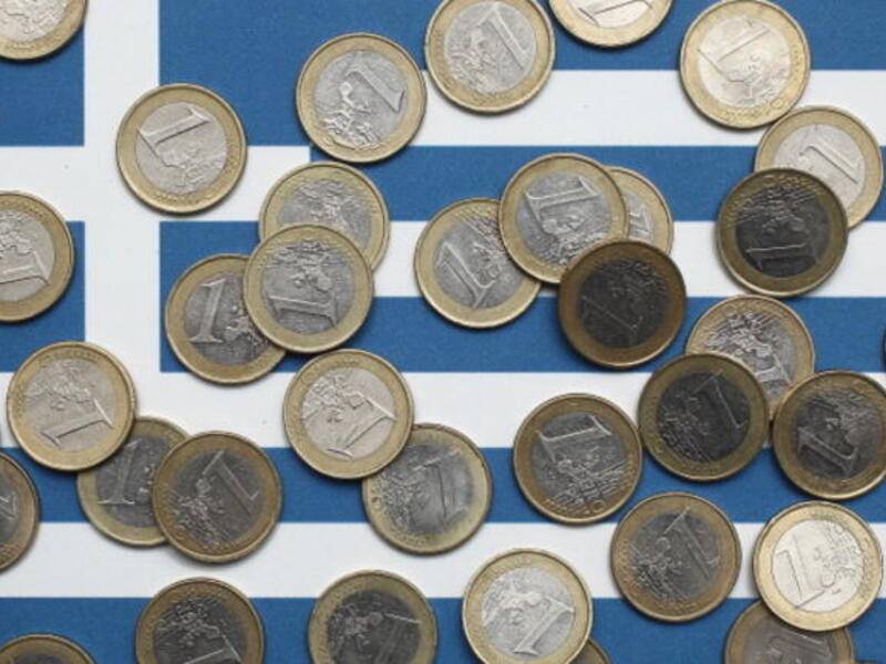 Euro coins atop a Greek flag