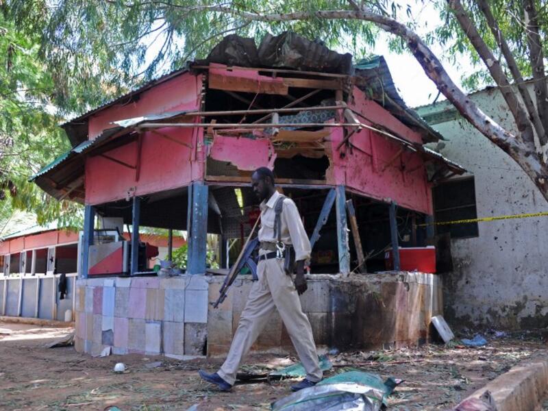 A Somali policeman walks at the scene of an explosion at the Village Restaurant in Mogadishu, on January 2, 2016. (AFP/Mohamed Abdiwahab)