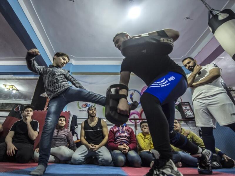 Syrian refugee Amir al-Awad (R) watches as Adel Bazmawi (C) teaches martial arts to youth at the academy in Egypt's Alexandria on Jan 4, 2018. The academy is squeezed into just 30 square metres, in a modestly equipped hall at the bottom of a residential building. The project began in 2016 with just $430 at the time.

KHALED DESOUKI / AFP