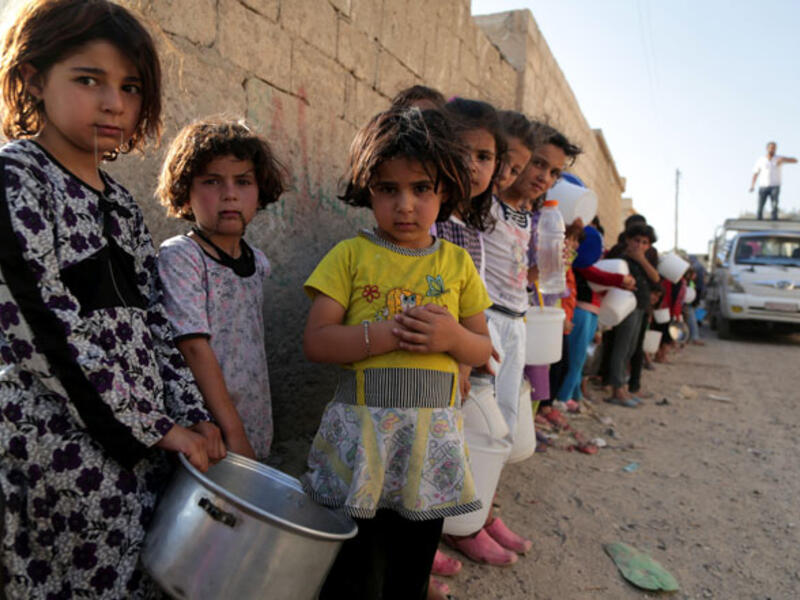 Displaced children in Raqqa, Syria line up for a free iftar meal to break the daily Ramadan fast, July 2013.  (AFP/Mezar Matar)