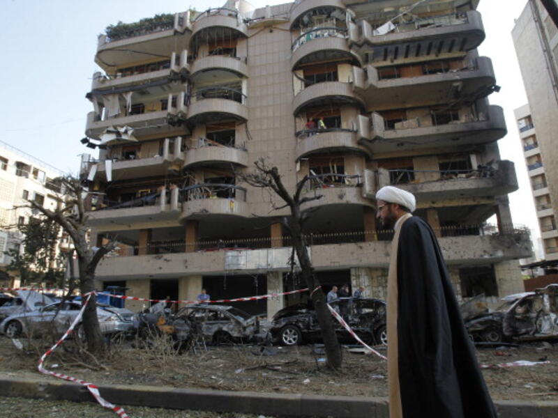 A Shiite cleric walks past a damaged building on November 20, 2013 at the scene of the previous day's double suicide bombing outside the Iranian embassy in Beirut. [AFP]