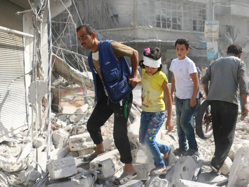Syrians walk over rubble following air strikes on the rebel-held Fardous neighbourhood of the northern embattled Syrian city of Aleppo on October 12, 2016. (AFP/Ameer Alhalbi)