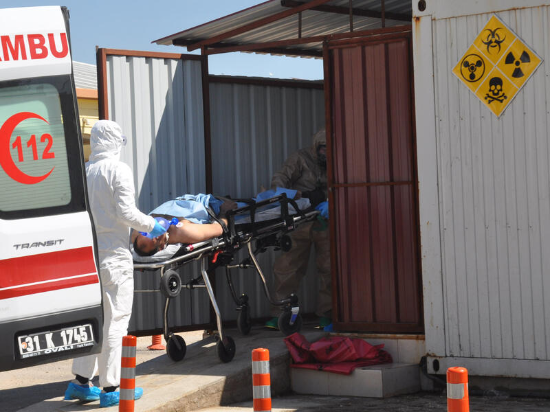 An injured Syrian is taken from an ambulance in Hatay province by Turkish officials wearing protective clothing, 4 April 2017. (AFP/Dogan News Agency)