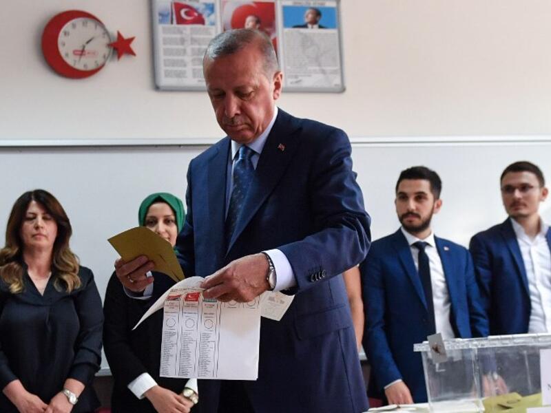 Turkey's President and leader of the Justice and Development Party (AKP) Recep Tayyip Erdogan looks at his ballot before casting his vote at a polling station during snap twin Turkish presidential and parliamentary elections in Istanbul on June 24, 2018.(Bulent Kilic/ AFP)