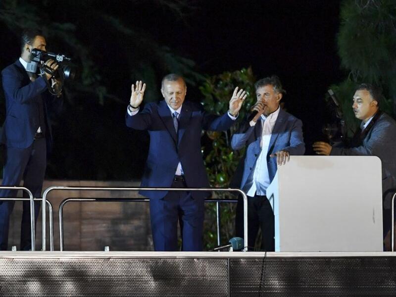 Turkish President Recep Tayyip Erdogan (C) waves to suppporters in Istanbul on June 24, 2018, during Turkey's presidential and parliamentary elections. Erdogan on June 24 declared victory in a tightly-contested presidential election. (AFP/ Bulent Kilic)