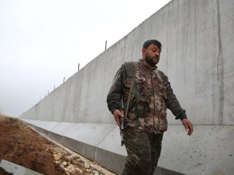 A YPG fighter walks along the Turkish-Syria border wall. (AFP/File)