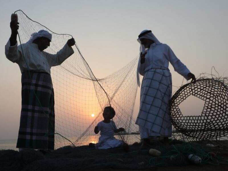 Emirati men train a child on handicraft industries during the Dalma Sailing Festival. (KARIM SAHIB / AFP) 


