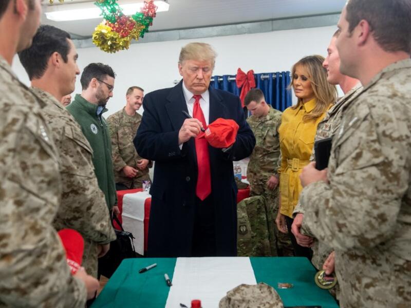 US President Donald Trump signs a hat as First Lady Melania Trump looks on as they greet members of the US military during an unannounced trip to Al Asad Air Base in Iraq on December 26, 2018. President Donald Trump arrived in Iraq on his first visit to US troops deployed in a war zone since his election two years ago. SAUL LOEB / AFP