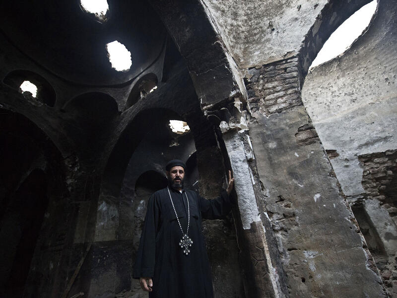A Coptic priest stands inside what remains of a church after it was attacked by arsonists.  (AFP/Khaled Desouki)