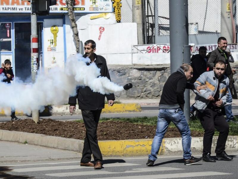 People react as a tear gas canister is thrown by Turkish police during clashes in central Diyarbakir on March 17, 2016. (AFP/Ilyas Akengin)