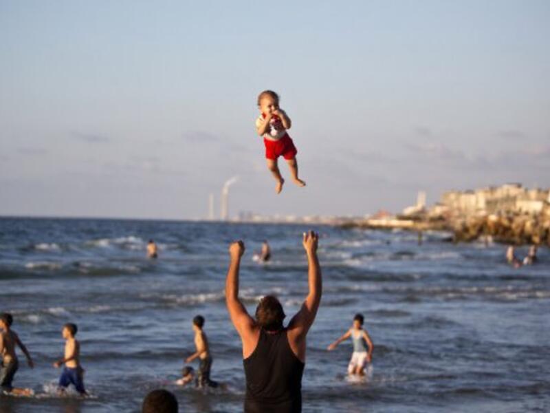 In a moment of calm following 2014's brutal war in Gaza, a man throws his laughing baby into the air on the beach in Gaza City.  Gaza's beaches, where last summer four boys were killed by Israeli missiles while playing soccer, are worlds away from the swanky seaside hangouts of Tel Aviv.  (AFP/Mahmud Hams)