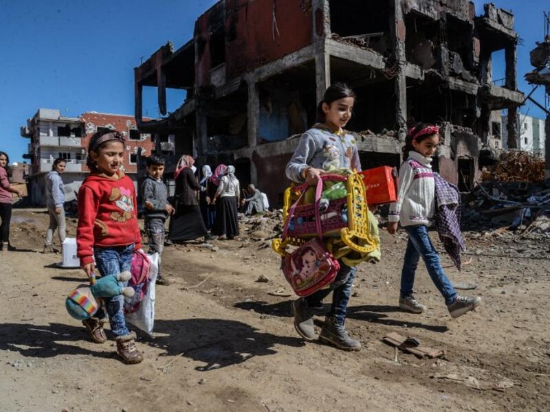 Young girls walk next to ruined houses and shops on March 8, 2016 during International Women's day in Cizre district. (AFP/Ilyas Akengin)