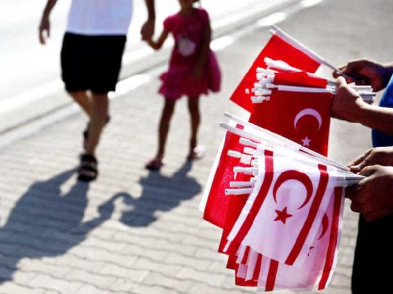 Greek officials and families at the memorial of soldiers killed in the 1974 coup (left). Tukish Cypriots holding their flags in a parade marking the 40th anniversary of Turkish invasion. (AFP/File)