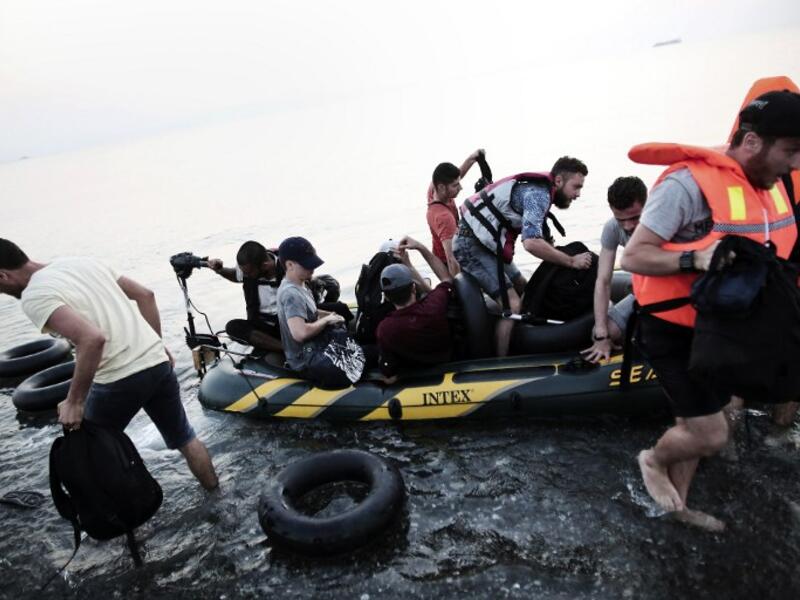A file photo shows migrants unloading a boat in the Aegean Sea. (AFP/File)