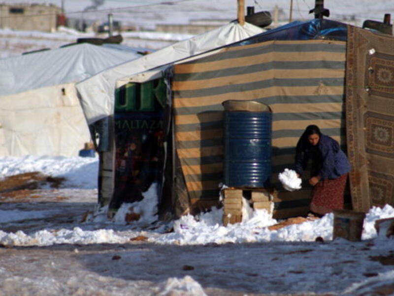 A Syrian woman shovels snow following a storm in the eastern Lebanese city of Baalbek on December 12, 2013. [AFP]