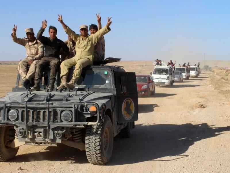 Iraqi government forces flash the sign for victory as they evacuate hundreds of Iraqis from the town of Hit in Anbar province on April 4, 2016. (AFP/Moadh al-Dulaimi)
