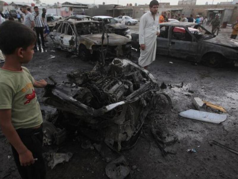Iraqis gather at the scene of one of the two car bombs that exploded near an used car dealerships in Baghdad's Habibiyah area on May 27(Ahmad Al-Rubaye/ AFP)