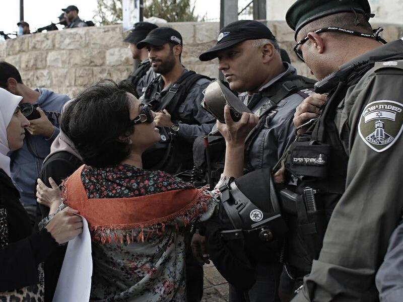A Palestinian woman blocked from entering the al-Aqsa Mosque compound, Islam's third most holy site, holds up a Quran during clashes with Israeli Occupation Forces on Oct. 13, 2014. (AFP/Ahmad Gharabli)