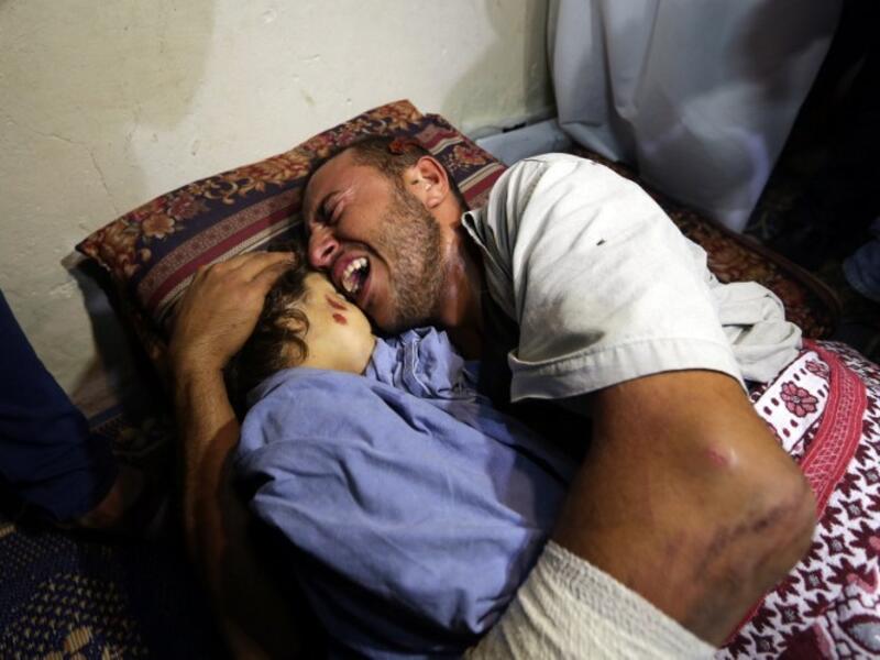 Palestinian father Yehya Hassan mourns while holding the body of his daughter, Rahaf, during a funeral for the toddler and her pregnant mother on Oct. 11, 2015, at the al-Nusairat refugee camp in central Gaza Strip. (AFP/Mahmud Hams)