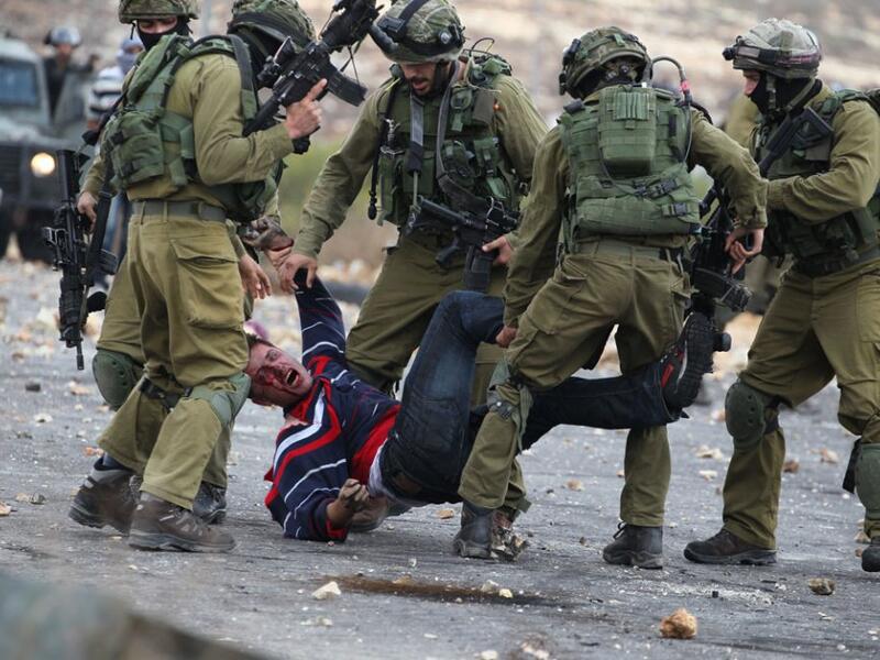 Israely soldiers detain a wounded Palestinian stone thrower during clashes in Beit El, on the 17 October 2015. (AFP /Abbas Momani)