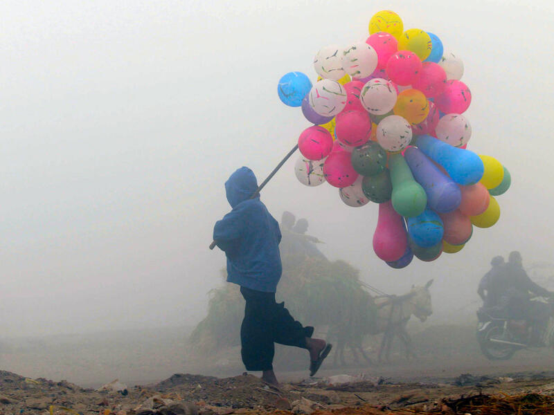 A balloon vendor walks through the fog in Lahore, Pakistan.  (AFP/Arif Ali)