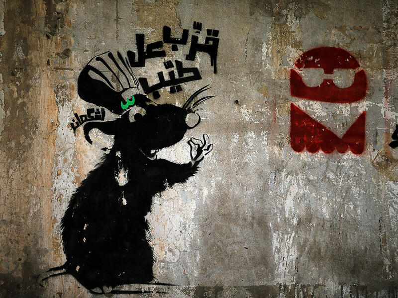 A rat beckons viewers to "come taste the goodies" above a pile of trash in Beirut, amidst Lebanon's garbage crisis.  (AFP/Joseph Eid)