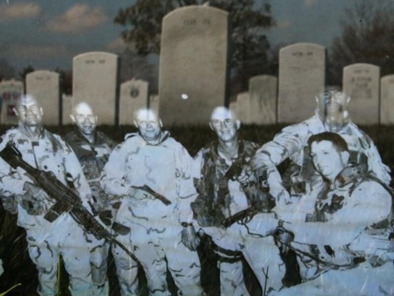 Headstones are reflected in a photograph that is leaning against the headstone for Iraq war casualty U.S. Army Master Sgt. Tulsa Tulaga Tuliau on the 10th anniversary of the beginning of the war in Iraq. (Getty Images/AFP)