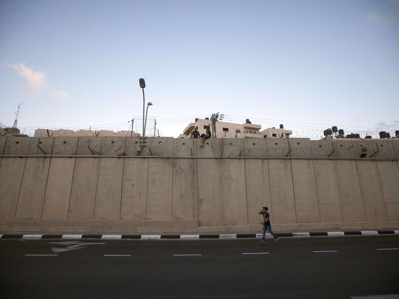 Palestinian men prepare to jump using a rope over a section of Israel's controversial concrete barrier that separates the West Bank from Jerusalem on August 12, 2013, in Beit Hanina, in Israeli annexed east Jerusalem. (AFP)