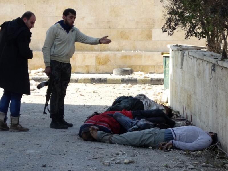 Rebel fighters gesture next to the bodies of handcuffed and blindfolded dead men laying on the ground of the Aleppo headquarters of the Islamic State of Iraq and the Levant. (AFP)

