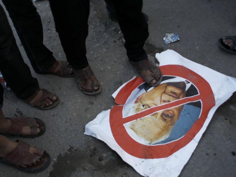 Palestinian supporters of the Islamic Jihad step on a poster bearing a portrait of former Israeli premier Ariel Sharon who died after being in a coma for eight years, aged 85. (AFP)