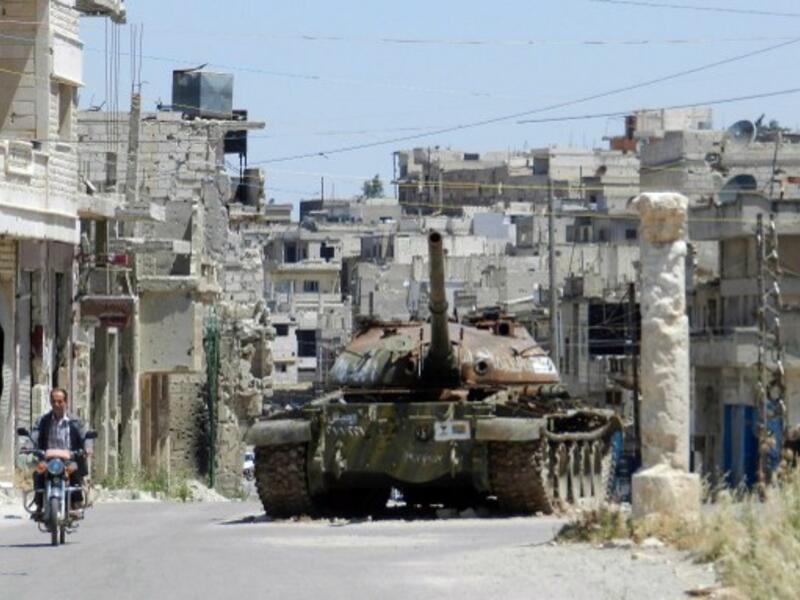 A man rides his motorbike past a burnt out Syrian Army tank in a central Homs province earlier this week. AFP image