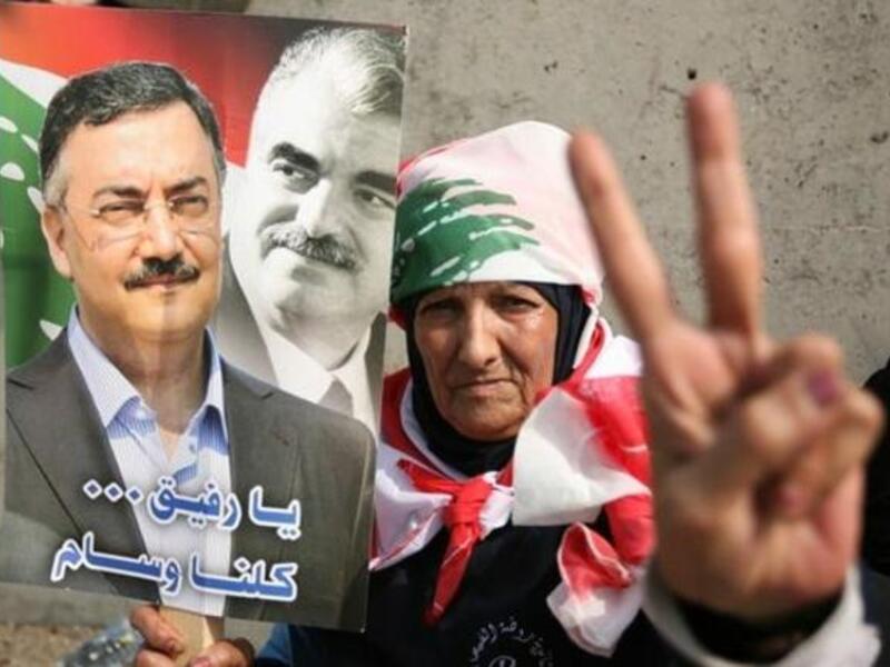 One of the mourners holds a picture of Hassan (left) with Rafiq Hariri (right): (picture courtesy of Hasan Shaaban/Daily Star)