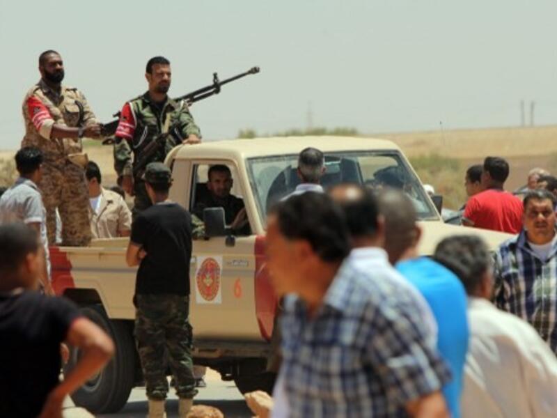 Libyan security personnel stand guard in an armed pick-up as residents of the eastern Libyan city of Benghazi bury the bodies of the demonstrators that were killed during clashes between former rebels and anti-militia protesters on Sunday. AFP 