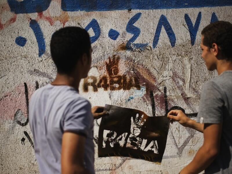 Supporters of the Muslim Brotherhood spray graffiti on the wall reading "Rabia", meaning four in a Arabic, and which has become a symbol to remember those killed in the crackdown on the Rabaa al-Adawiya camp, on August 23, 2013. (AFP)