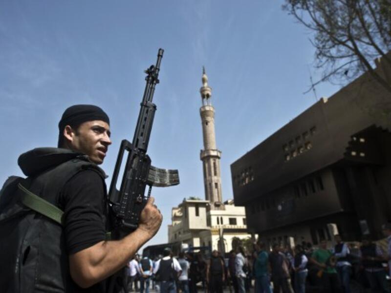 An Egyptian armed policeman holds a position in front of a burnt police station in the village of Kerdasa on the outskirts of Cairo, on September 19, 2013. (AFP)
