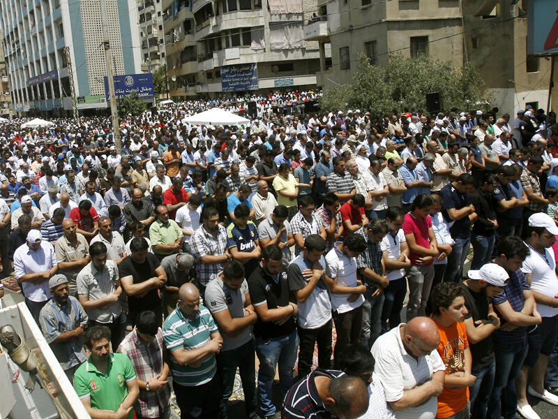 Supporters of Lebanon's radical Sunni cleric Sheikh Ahmad al-Assir perform the weekly Friday prayers as they gather to show their support to Assir in the southern city of Sidon on June 28, 2013. Lebanese security forces have launched a manhunt for Assir, after clashes with his supporters in Sidon killed 17 soldiers. (Source: AFP/MAHMOUD ZAYYAT)