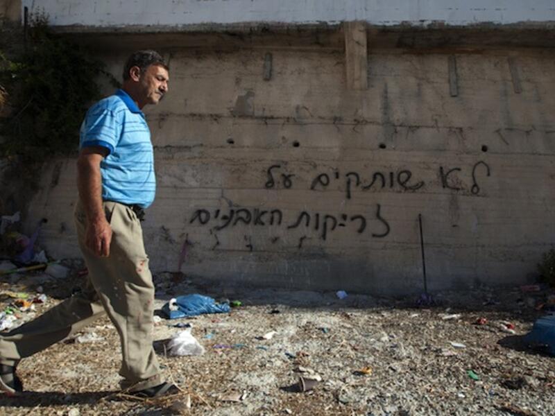 A Palestinian man was past graffiti that reads in Hebrew, "'We do not remain silent in face of stone throwing" as he walks past a wall in the Arab east Jerusalem neighborhood of Beit Hanina, on Monday. (AFP)