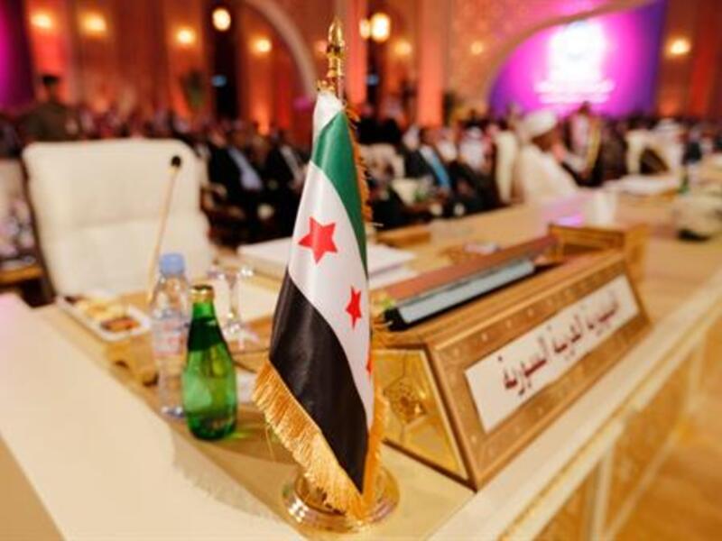 The flag of the Syrian opposition is shown at the seat of the delegation representing Syria at the Arab League summit in Doha in March. Image courtesy of The Daily Star