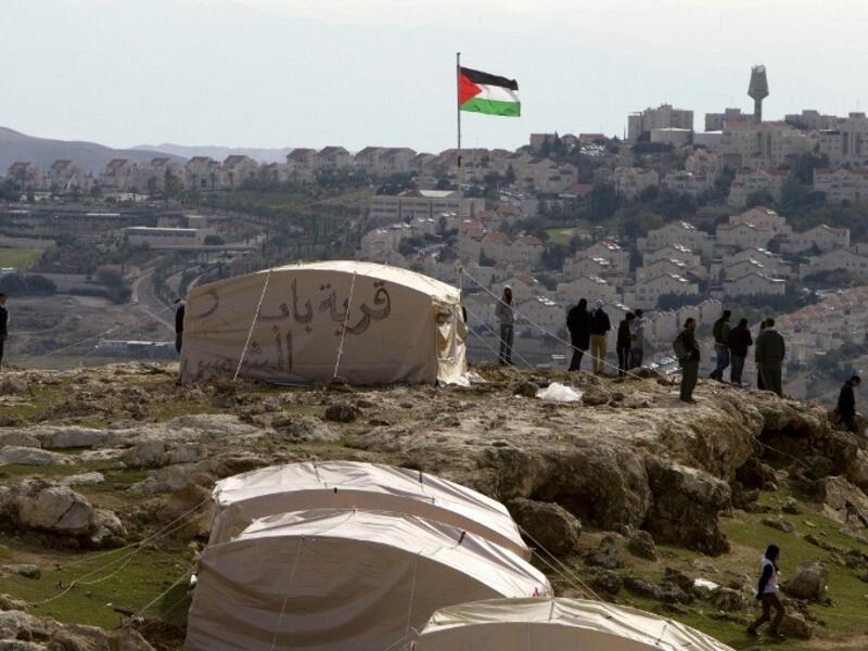 A Palestinian flag flutters as Palestinians, together with Israeli and foreign activists, stand near tents at the Bab al-Shams (Gate of the Sun) 'outpost' in the sensitive West Bank corridor east of Jerusalem on Saturday (Photo: AFP /AHMAD GHARABLI)