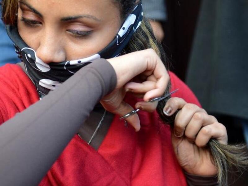 An Egyptian women cutting her hair in protest at the new constitution