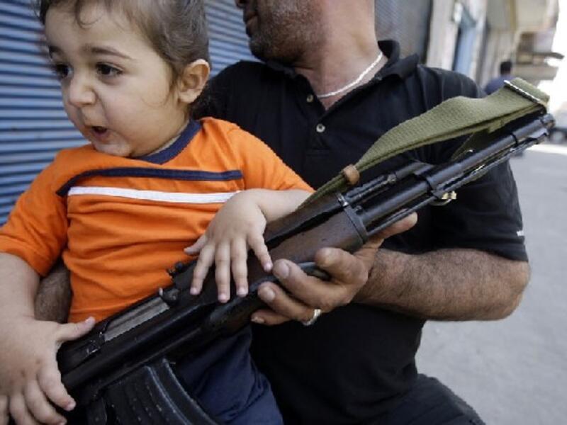 A Sunni Muslim gunman sits with his child on Syria Street during fighting in the Bab al-Tebbaneh neighbourhood of the northern Lebanese city of Tripoli. AFP Photo/Getty Images