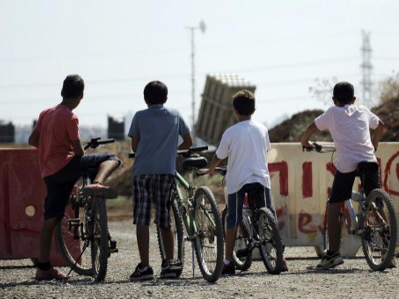 Israeli boys stand with their bicycles as they watch a battery of Iron Dome, a short-range missile defence system, positioned on the outskirts of Tel Aviv on August 30, 2013. (AFP)